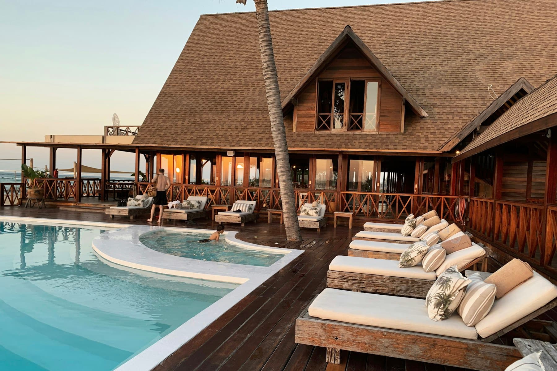 Nachhaltiges Resort mit Pool und Holzarchitektur am Meer bei Abendlicht